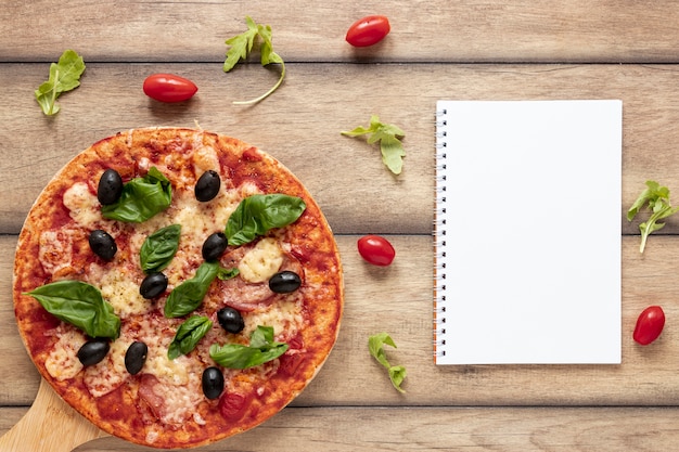 Draufsichtanordnung mit Pizza und Notizbuch