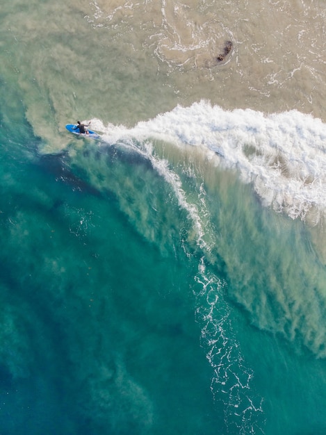 Draufsichtaufnahme einer Person mit einem Surfbrett, das in Varkala Beach schwimmt