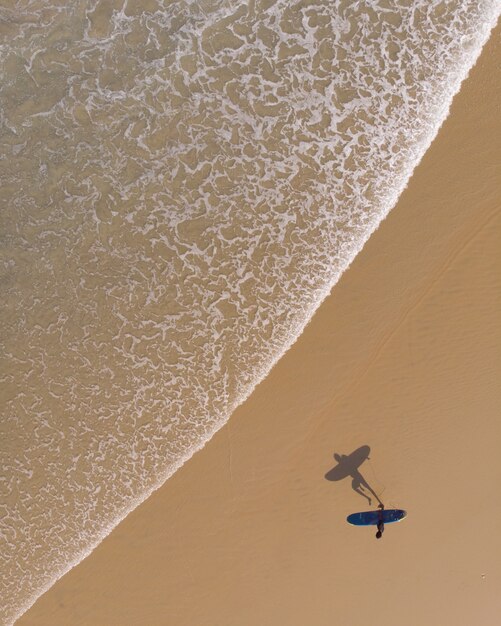 Draufsichtaufnahme einer Person mit einem Surfbrett, das in Varkala Strand geht