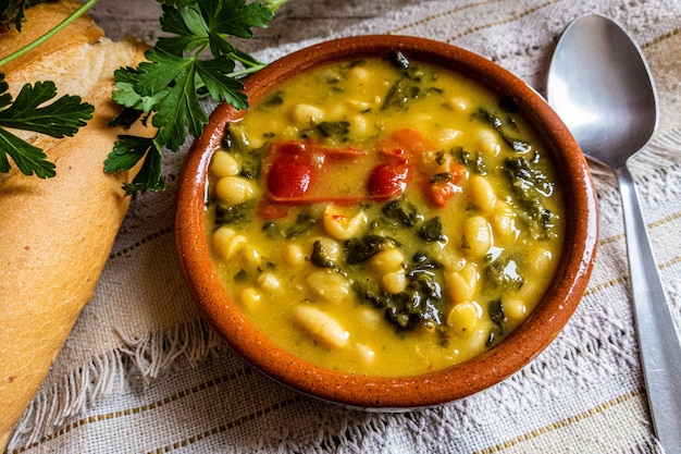 Draufsichtaufnahme von Gemüsesuppe in der Tonschüssel mit Brot und Gemüse auf dem Tisch