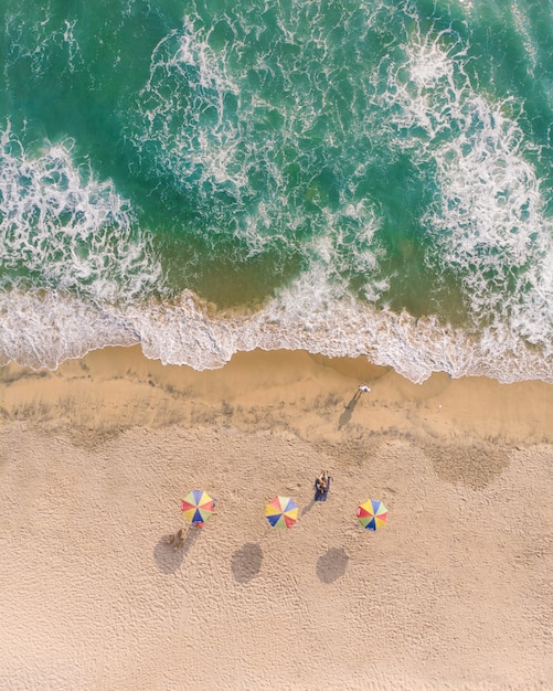 Draufsichtaufnahme von Sonnenschirmen und Leuten, die auf dem Sand in Varkala Beach liegen