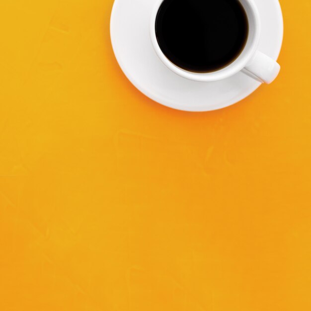 Draufsichtbild der Kaffeetasse auf hölzernem gelbem Hintergrund