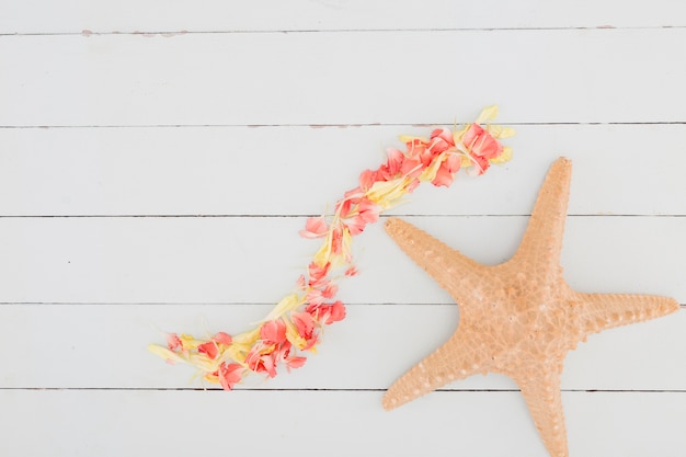 Kostenloses Foto draufsichtblumenblätter und -starfish auf hölzernem hintergrund