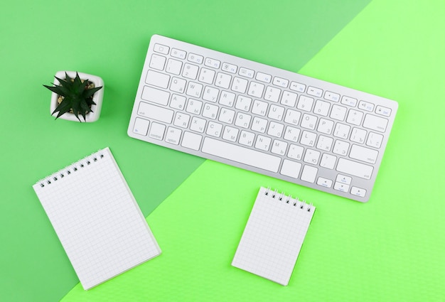 Draufsichtbriefpapieranordnung auf grünem Hintergrund mit leeren Notizblöcken