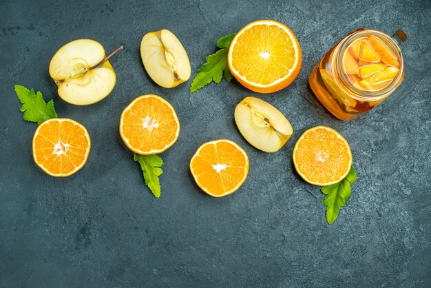 Draufsichtcocktail geschnittene Orangen und Äpfel auf dunklem, isoliertem Hintergrund
