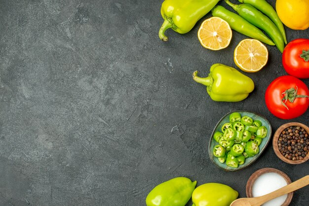 Draufsichtgemüsezusammensetzung Tomaten Paprika und Zitrone auf dunklem Hintergrund