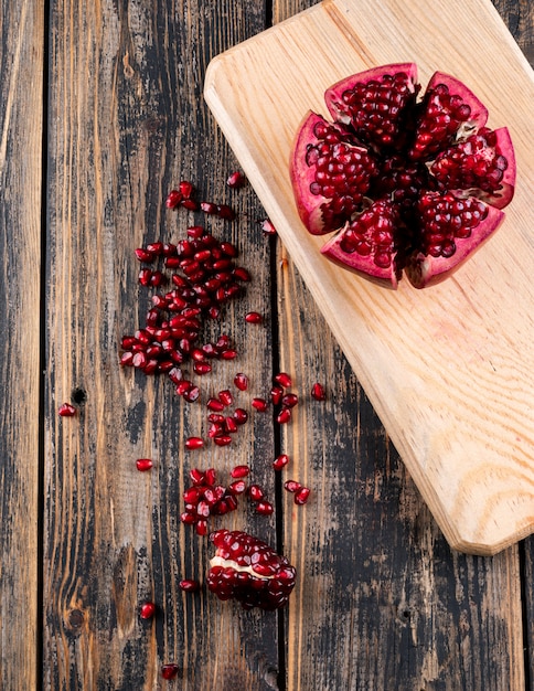 Kostenloses Foto draufsichtgranatapfel auf hölzernem schneidebrett auf tabelle