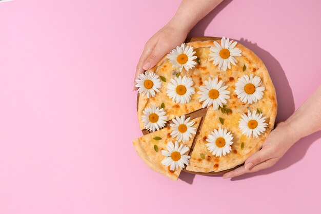 Draufsichthände, die pizza auf rosa hintergrund halten