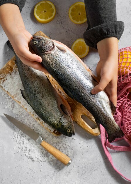 Draufsichthände, die rohe forelle kochen