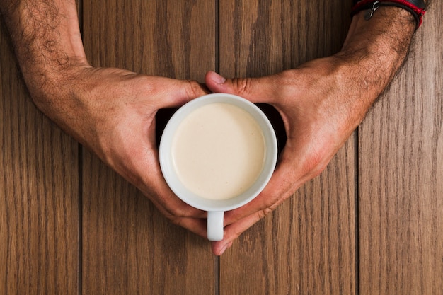 Draufsichthände, die tasse kaffee halten