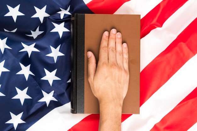 Draufsichthand auf Buch und amerikanischer Flagge