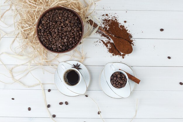 Draufsichtkaffee in der Tasse mit gemahlenem Kaffee, Gewürzen, Kaffeebohnen auf hölzernem Hintergrund. horizontal