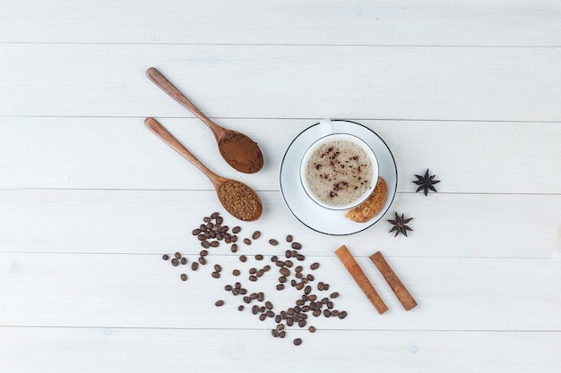 Draufsichtkaffee in der Tasse mit gemahlenem Kaffee, Gewürzen, Kaffeebohnen, Keksen auf hölzernem Hintergrund. horizontal