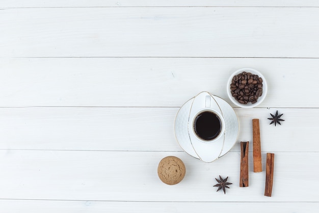 Draufsichtkaffee in der Tasse mit Kaffeebohnen, Gewürzen, Keks auf hölzernem Hintergrund. horizontal