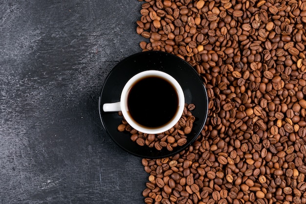 DraufsichtKaffeetasse und Kaffeebohnen auf dunkler Tabelle