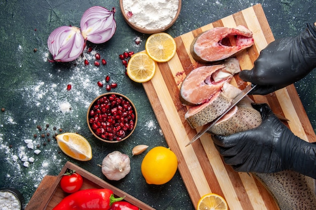 Draufsichtkoch, der rohen Fisch auf Schneidebrett Mehlschüssel Zitrone auf Tisch schneidet