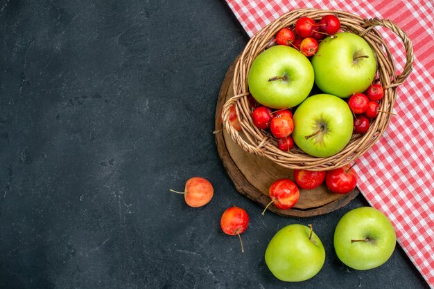 Draufsichtkorb mit Früchten grüne Äpfel und Süßkirschen auf dunkelgrauer Oberfläche Früchte Beerenzusammensetzung Frische Baum
