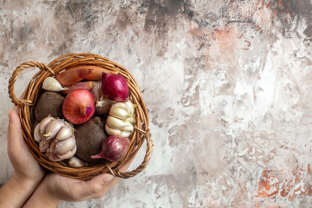 Draufsichtkorb mit Gemüse-Knoblauch-Zwiebeln und -Rüben auf heller Fotofarbe reifer Salatdiät freier Raum