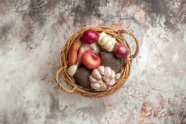 Draufsichtkorb mit Gemüse, Knoblauch, Zwiebeln und Rüben auf leicht reifem Salat Fotodiät