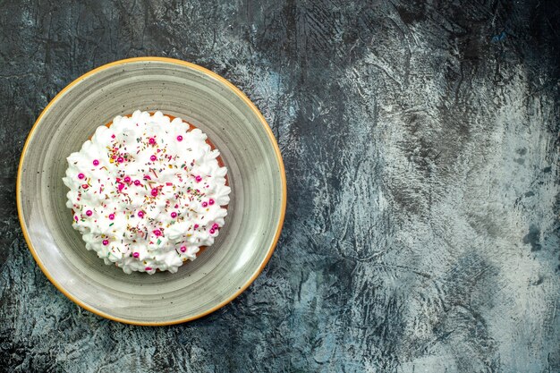 Draufsichtkuchen mit Gebäckcreme auf grauer runder Platte auf grauem Tisch mit Kopienraum
