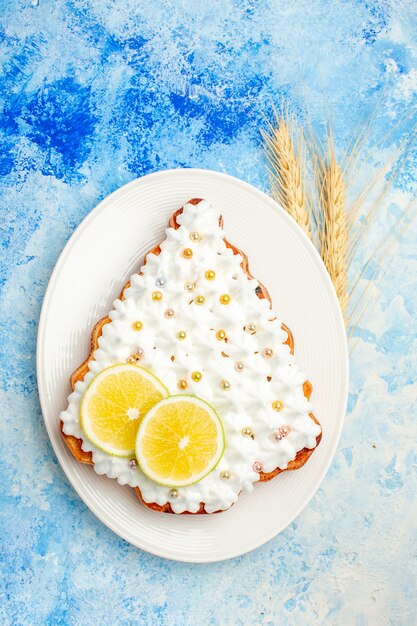 Draufsichtkuchen mit Gebäckcreme und Zitrone auf Teller auf blauem Tisch