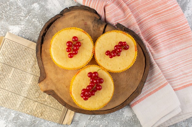 Draufsichtkuchen mit Preiselbeeren lecker gebacken auf dem hölzernen Schreibtisch und grauem Hintergrundzuckersüßbacken