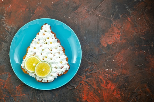 Draufsichtkuchen mit Zitrone auf blauem Teller auf dunkelrotem Hintergrund