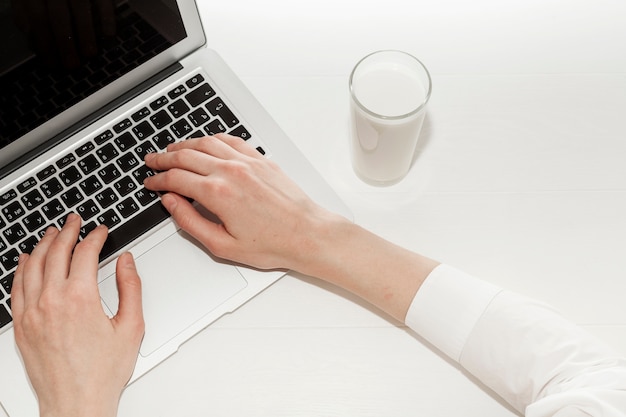 Draufsichtmädchen, das an ihrem Laptop nahe bei einem Glas Milch arbeitet