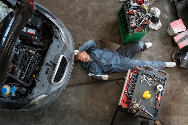 Kostenloses Foto draufsichtmann, der auto repariert