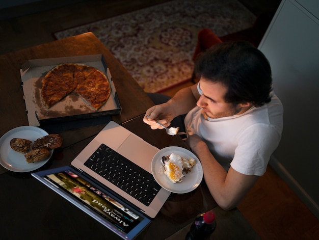 Kostenloses Foto draufsichtmann mit snack und laptop