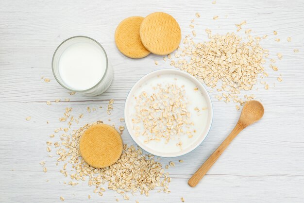 Draufsichtmilch mit Haferflocken zusammen mit Glas Milch und Keksen auf weißer Milchmilchfrühstücksgesundheit