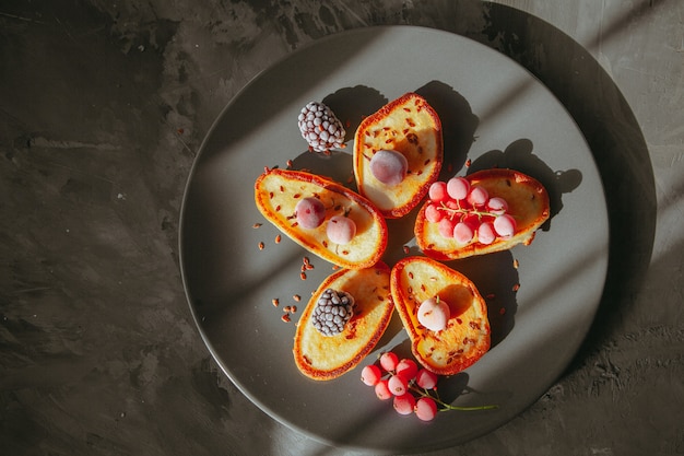 Draufsichtpfannkuchen im Teller mit Brombeeren und Preiselbeeren auf strukturiertem Tisch. horizontal