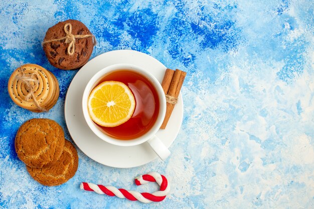 Draufsichtplätzchen gefesselt mit Seiltasse Tee Weihnachtssüßigkeiten auf blauem Tisch