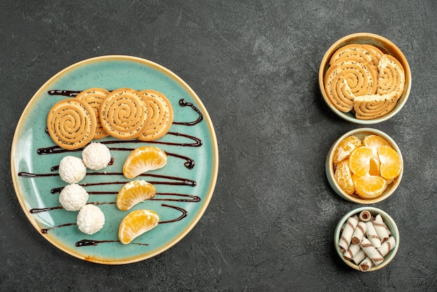 Kostenloses Foto draufsichtplätzchen und bonbons mit mandarinen auf dem grauen tisch süße keksplätzchen