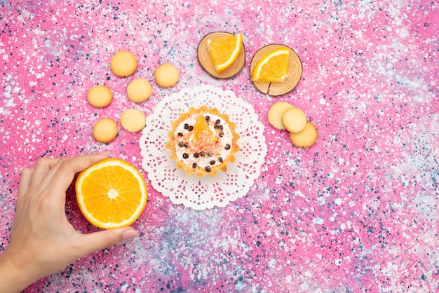 Draufsichtplätzchen und Kuchen mit Orangenscheiben weiblich, die Orange auf dem farbigen Oberflächenplätzchenplätzchenfruchtkuchen süß nehmen