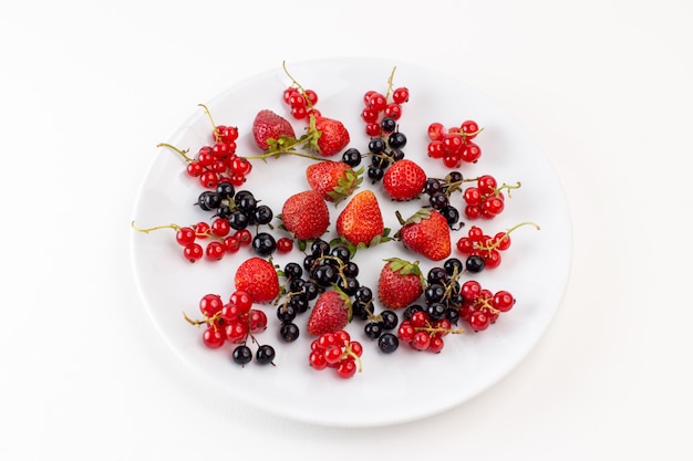 Draufsichtplatte mit Erdbeeren frisch und mild mit Blaubeeren auf der weißen Hintergrundfarbe frische milde Fruchtbeere