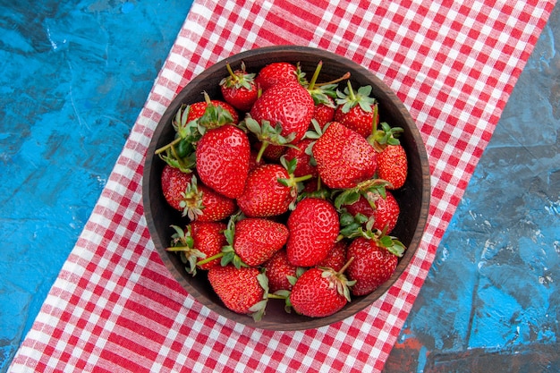 Draufsichtplatte mit frischen leckeren reifen früchten der erdbeeren auf blauem hintergrund