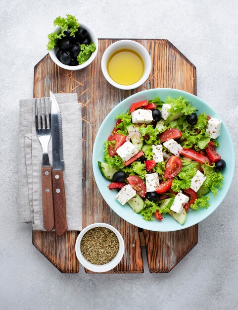 Draufsichtsalat mit Feta-Käse auf Schneidebrett mit Oliven und Kräutern