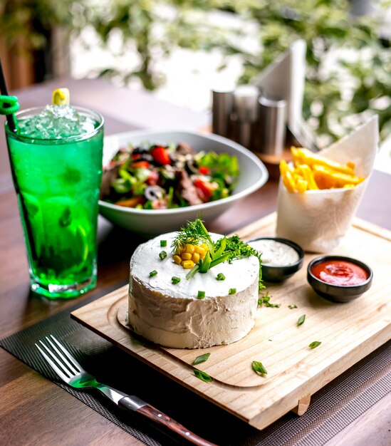 Draufsichtsalat mit saurer Sahne mit Pommes Frites auf einer Tafel mit einem alkoholfreien Getränk