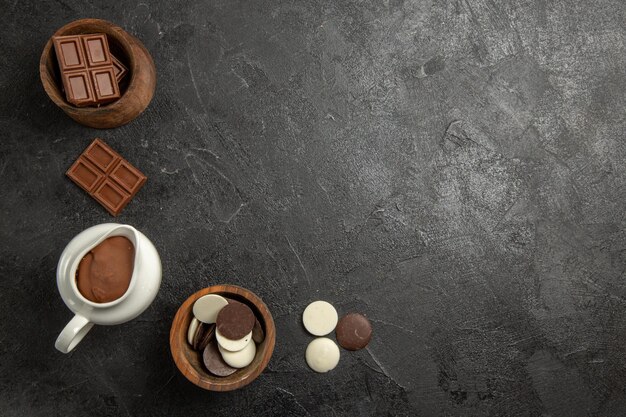 Draufsichtschokolade auf dem Tisch Schokolade und Schokoladencreme in den Holzschalen auf dem schwarzen Tisch