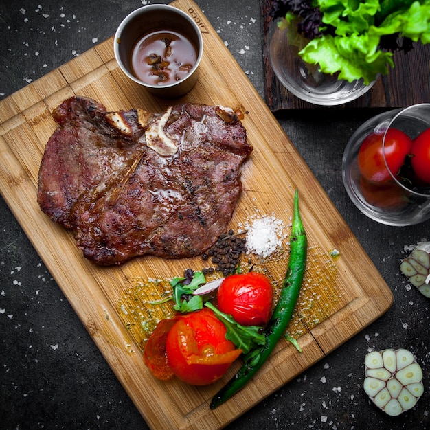 Draufsichtsteak mit Tomate und Papier im Steakbrett