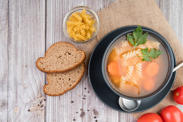 Draufsichtsuppe in Schüssel mit Brot und Tomaten