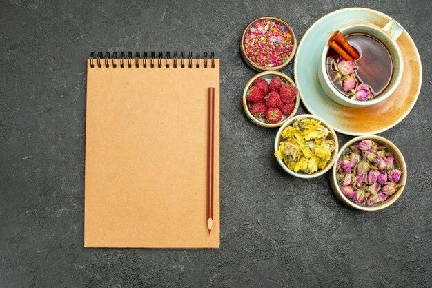 Draufsichttasse tee mit blumen und himbeeren auf dem dunklen hintergrund tee-fruchtgetränk-geschmacksblume