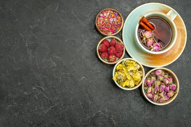 Draufsichttasse tee mit blumen und himbeeren auf dem dunklen hintergrund tee-fruchtgetränk-geschmacksblume