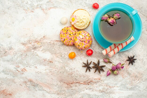 Draufsichttasse tee mit cremigen kuchen auf weißer oberflächentee-dessert-kekskuchen-torte