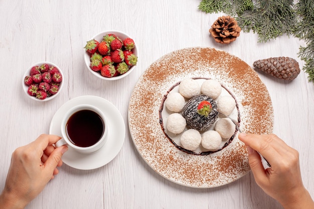 Draufsichttasse Tee mit Früchten und Kokosbonbons auf weißem Schreibtischfruchttee-Beeren-Kekskuchen cookie