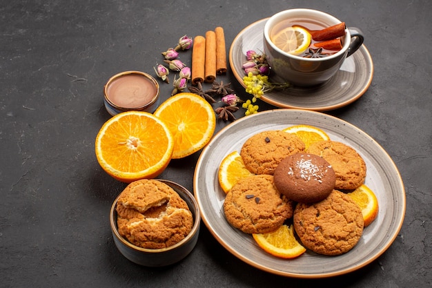 Draufsichttasse tee mit keksen und frisch geschnittenen orangen auf dunkler oberfläche tee zuckerfruchtkeks süßer keks