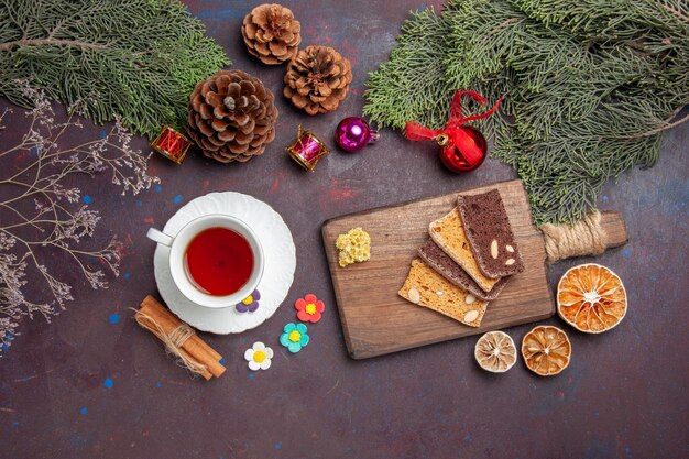 Draufsichttasse Tee mit Kuchenscheiben auf dem dunklen Raum the