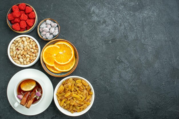 Draufsichttasse Tee mit Nüssen, Rosinen und Konfitüren auf dem dunklen Oberflächentee-Nuss-Snack