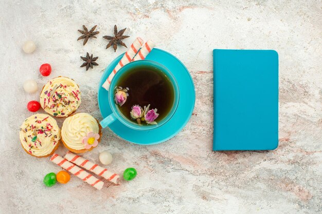 Draufsichttasse tee mit süßigkeiten und kuchen auf weißer oberfläche tee-dessert-kekskuchen-torte